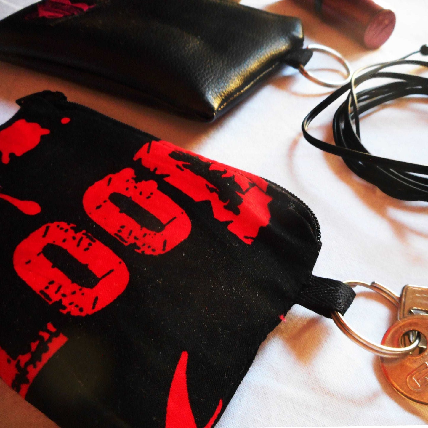 Kleine Münztasche mit aufgedruckten Fledermäusen und Blutflecken, schließt mit einem Reißverschluss und hat an der Seite einen Schlüsselring.