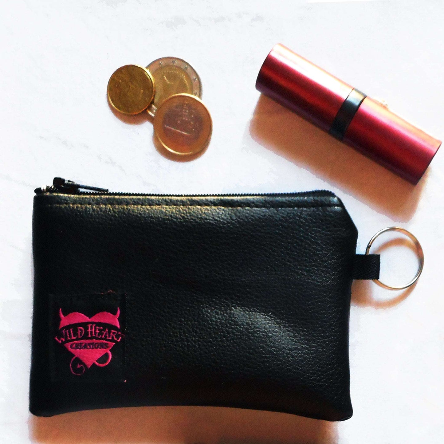 Schwarze kleine Münztasche aus schwarzem Kunstleder und Schlüsselring an der Seite.