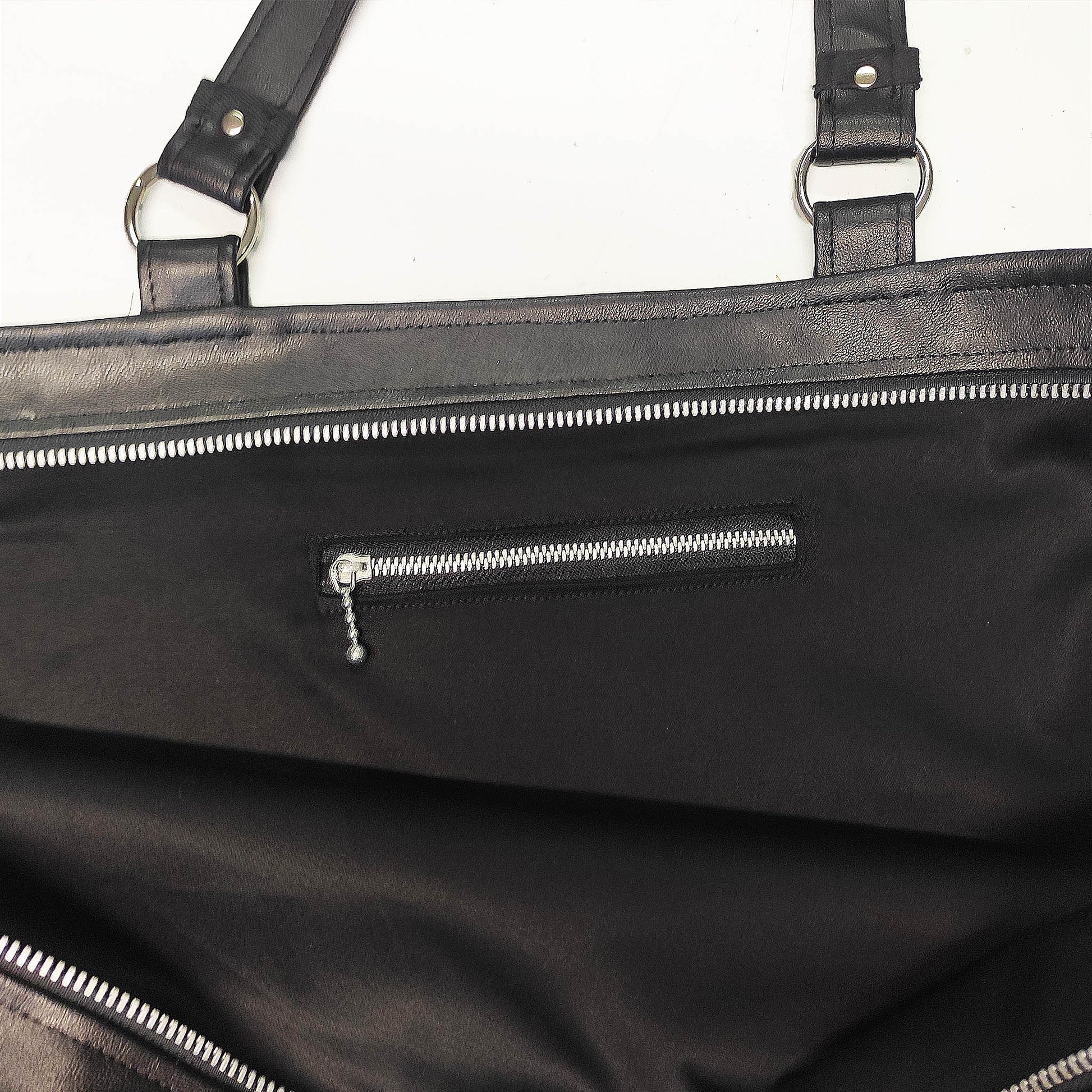 Handgemachte Tasche aus schwarzem Lederimitat und schwarzen Fransen an der Seite.