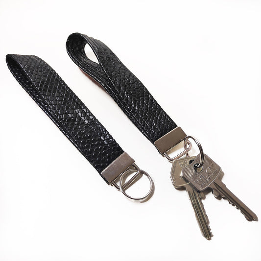 Handgemachter Schlüsselanhänger der aus schwarzem Lederimitat mit Krokodil Optik gefertigt ist. Dieser praktische Anhänger kann bequem um das Handgelenk getragen werden, sodass er jederzeit griffbereit ist.
