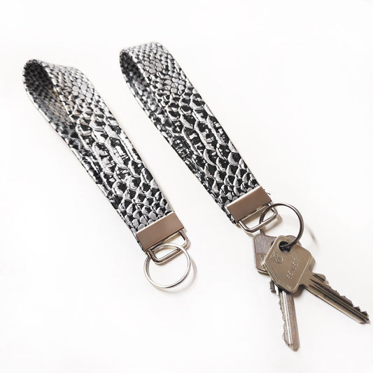 Handgemachter Schlüsselanhänger aus silbernem Lederimitat mit Krokodil Optik. Dieser praktische Anhänger kann bequem um das Handgelenk getragen werden, sodass er jederzeit griffbereit ist.