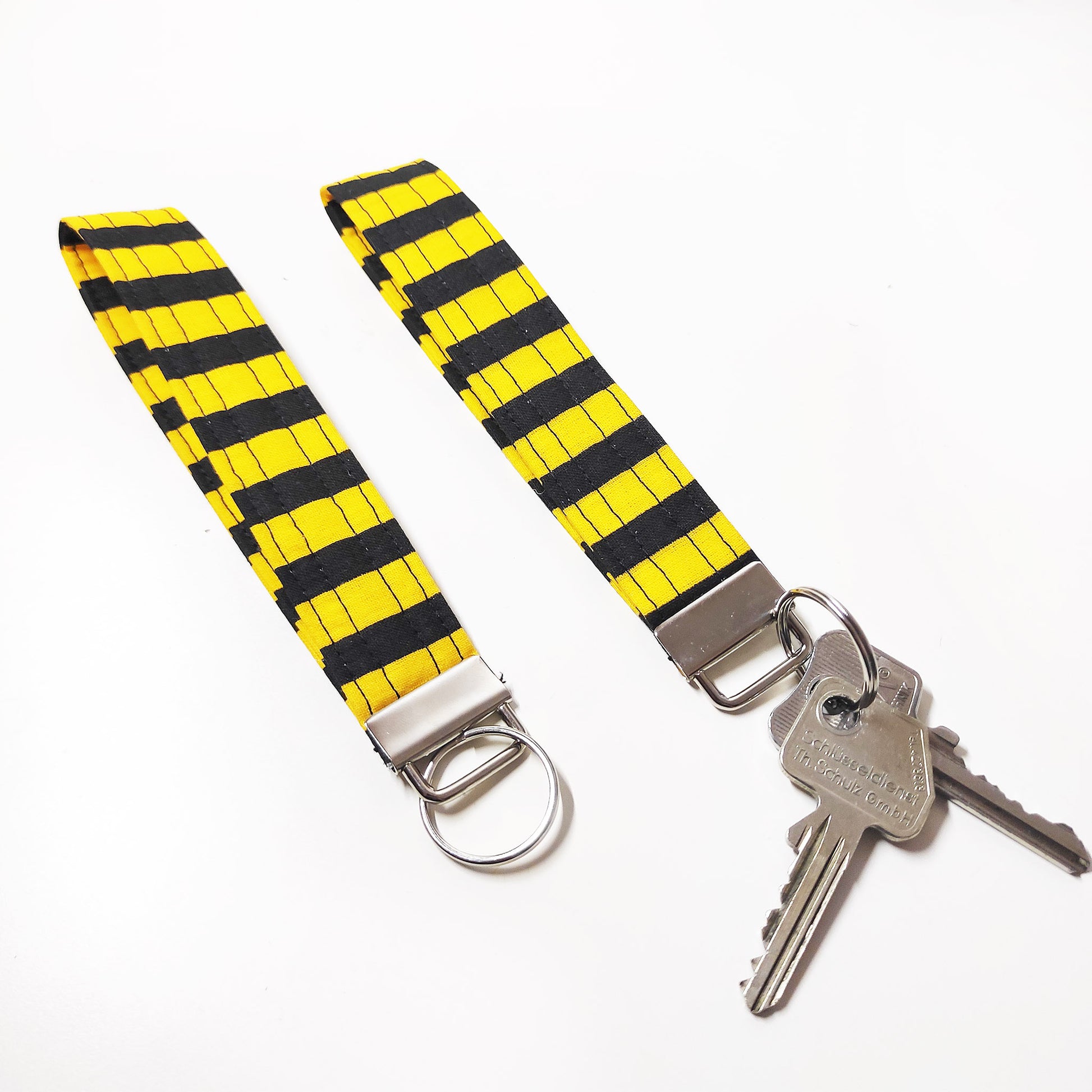 Handgemachter Schlüsselanhänger in gestreiftem gelb und schwarz. Dieser praktische Anhänger kann bequem um das Handgelenk getragen werden, sodass er jederzeit griffbereit ist.