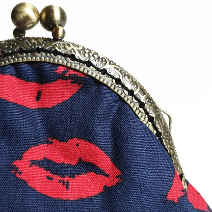 Geldbörse in dunkel blau mit bedruckten roten Lippen drauf. Sie schließt mit einen  Bronzefarbenen Kuss-Verschluss welcher mit mit nostalgischen Vintage-Schnitzereien verziert ist. 