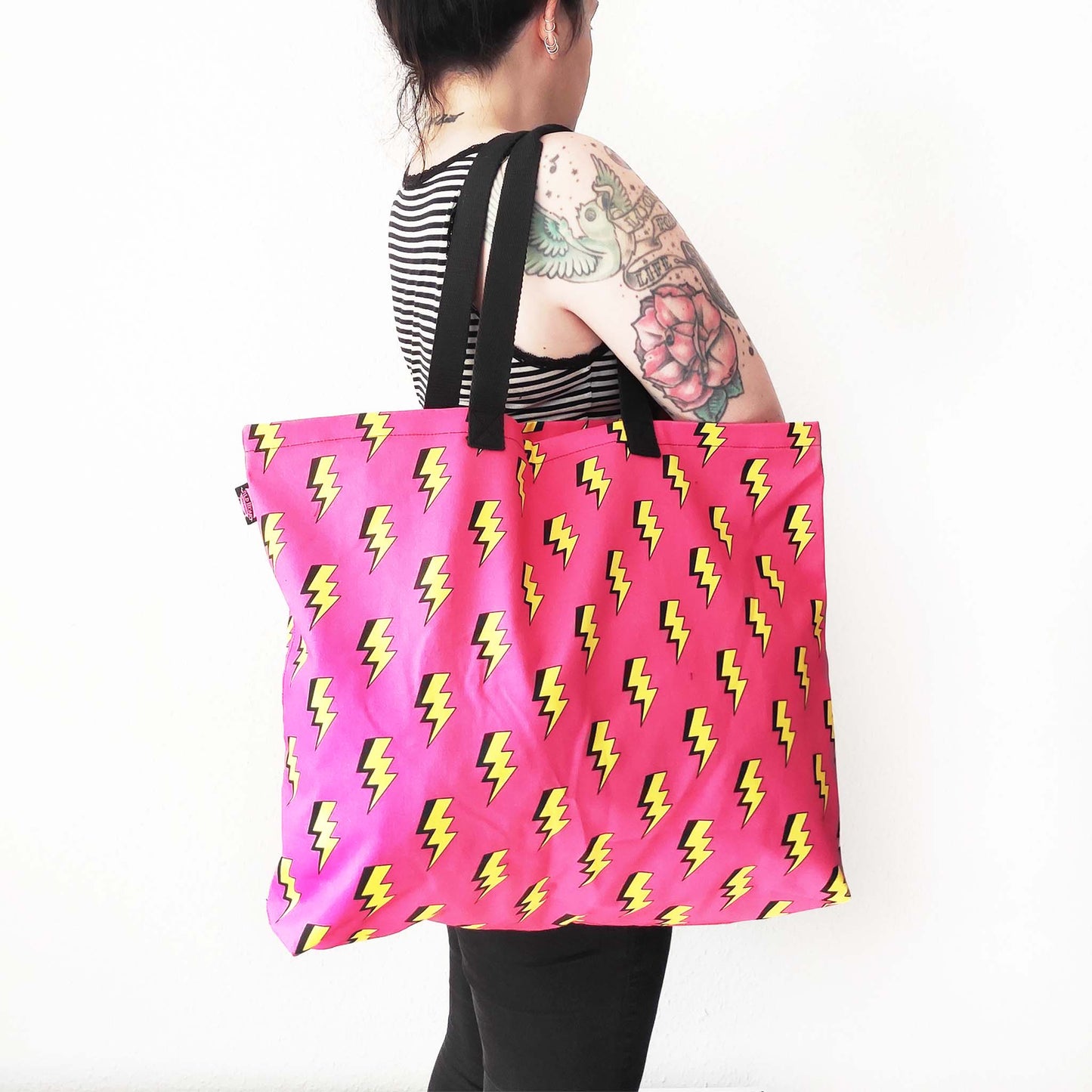Shopper Tasche mit auffälligen Blitzmotiv auf leuchtend pinkem Hintergrund.