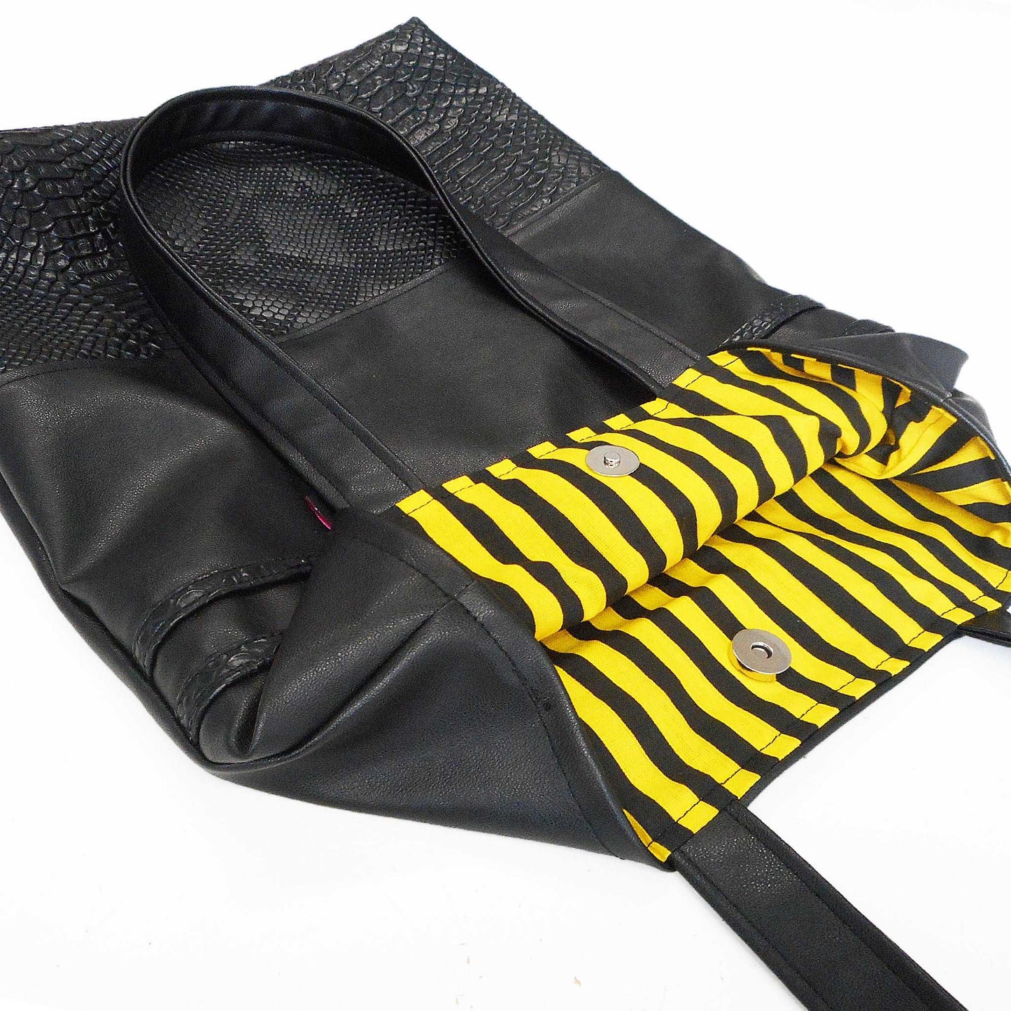 handgemachtes einzelstück. Tote Tasche aus schwarzem Ledermitat kombiniert mit Lederimitat in Schlangenoptik und gestreiftem Futter in Gelb und Schwarz.